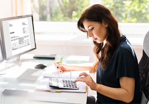Woman doing accounting work at a computer with a calculator